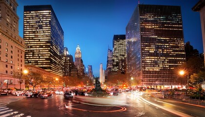Naklejka premium illuminated cars driving around columbus circle in the bustling new york city at night