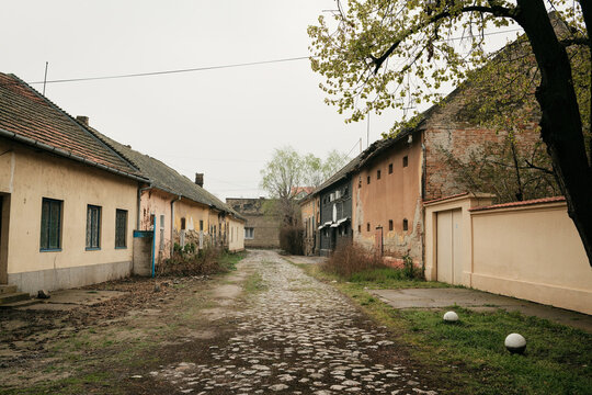 Old narrow street with cobblestone road and worn houses in Senta, Serbia. The scene shows rural urban life with nostalgic and quiet atmosphere.