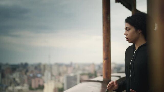 Young Black woman looking at city from a rooftop, facing her fear of heights