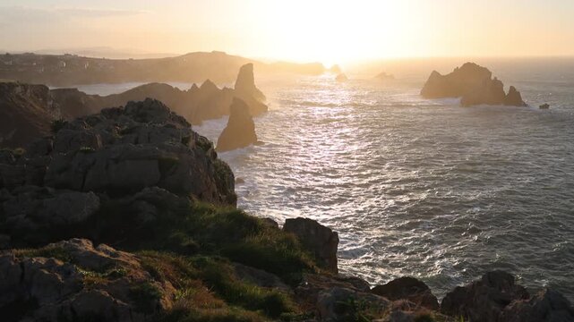 View of the Urros de Liencres sea stacks and rugged cliffs during a golden sunset in Liencres, Cantabria, Spain.