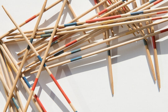 Colorful Mikado sticks scattered on a white background with sharp shadows. Traditional pick-up sticks game representing strategy, patience, precision, and risk management.