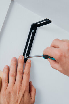 a man fastening a screw in a wall bracket