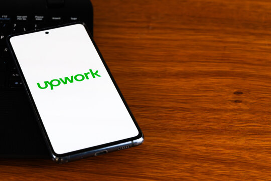 Punta Arenas, Chile &ndash; March 31, 2026: The Upwork logo displayed on a smartphone screen placed on a wooden desk next to a laptop keyboard