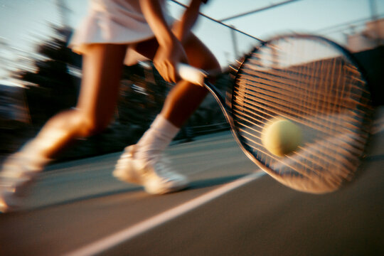 Low angle woman playing tennis on the court, motion blur effect