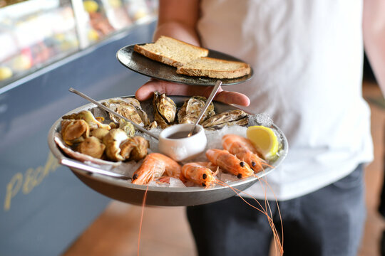 Fresh seafood platter with shrimp oysters served by waiter hands