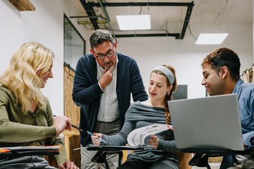 Naklejka premium hispanic senior man teacher with multicultural group of university students talking in classroom. Diverse group of people in Education concept