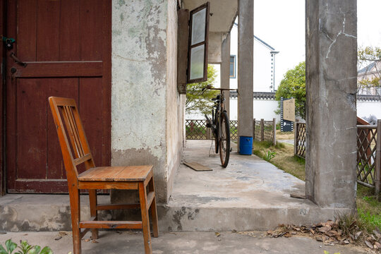 Old house entrance with wooden chair, bicycle, and weathered wall surface