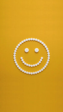 Smiley face made of white medicine pills on yellow background, Generative AI