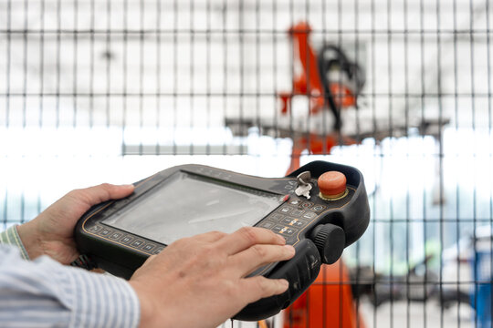 Worker holding an industrial robot teach pendant for operation and control