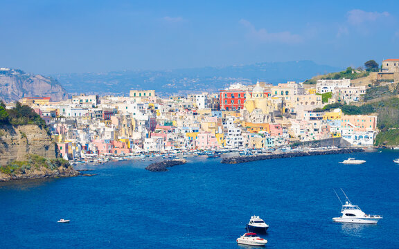 Colorful houses, cafes and restaurants, yachts and fishing boats in Marina Corricella, Procida Island, Italy. Picturesque Procida in sunny day