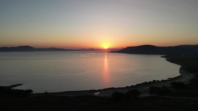 Aerial sunset view over Paralia Skidi beach on Limnos Island, Greece. Golden Mediterranean light reflects across calm sea and quiet shoreline, capturing peaceful natural scenery and evening atmosphere