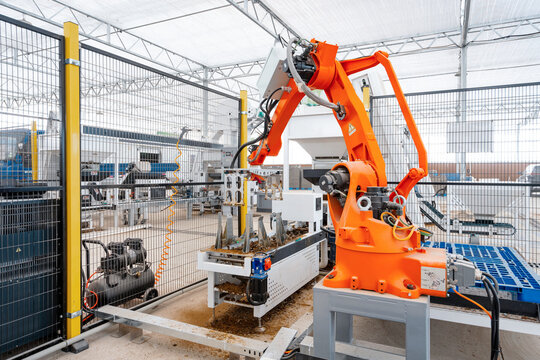 Orange industrial robotic arm operating on an automated production line in a factory