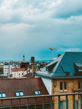 Moody European Cityscape with Historic Rooftops, Church Towers  under Dramatic Cloudy Sky