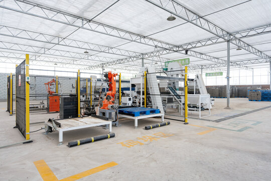 Industrial factory interior with automated robotic arm operating on production line