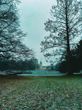 Snowfall Serenity in a Historic European Park with a Baroque Palace Tower Framed by Bare Winter Trees