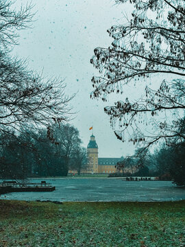 Snowfall Serenity in a Historic European Park with a Baroque Palace Tower Framed by Bare Winter Trees