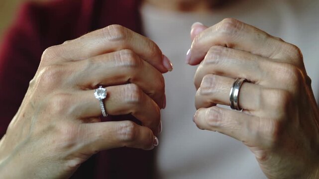Close-up of two hands with wedding rings interlocked, symbolizing love and commitment.