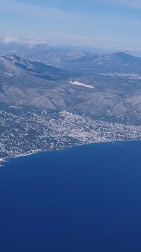 Vertical aerial view of Zoumperi and Nea Makri coastline. Topographic flight perspective showing urban planning, coastal infrastructure, and the geographic transition from Aegean Sea to Attica.