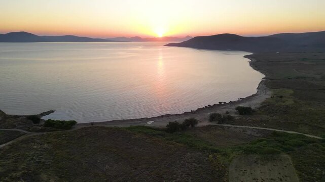 Aerial sunset view over Paralia Skidi beach on Limnos Island, Greece. Golden Mediterranean light reflects across calm sea and quiet shoreline, capturing peaceful natural scenery and evening atmosphere