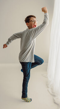Boy with glasses dancing playfully in bright studio portrait