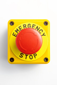 Red emergency stop button on a yellow box, isolated on white background. Professional industrial safety equipment for machinery control and emergency protocols.
