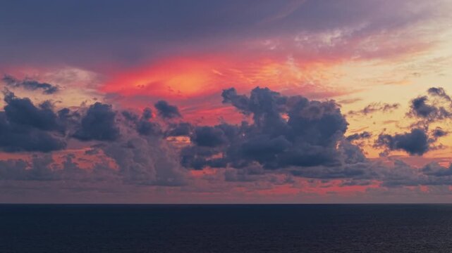 4K timelapse of vibrant orange and purple clouds moving across the sky, creating a dramatic and colorful atmospheric scene perfect for nature and cinematic projects.