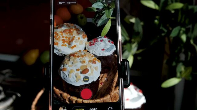 Italian Easter bread colomba pasquale arranged on table as female hands film soft paska and kulich on mobile phone for food blog with festive bakery details