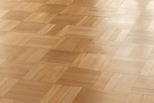 Smooth oak parquet hardwood floor with a warm natural finish and subtle sheen. Geometric square pattern creates a minimalist interior background ideal for design, architecture, product mockups