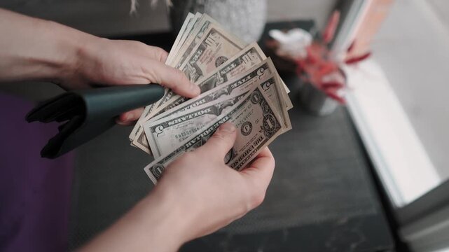 A male investor looks at his savings and profits in dollars in close-up. Currency and banknotes of the American government and the economy. Money in the wallet and salary