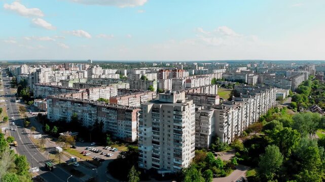 Drone shot of the 10th microdistrict in Sumy, Ukraine, with densely built-up residential buildings in a typical residential area. A busy road with moving traffic, green urban areas