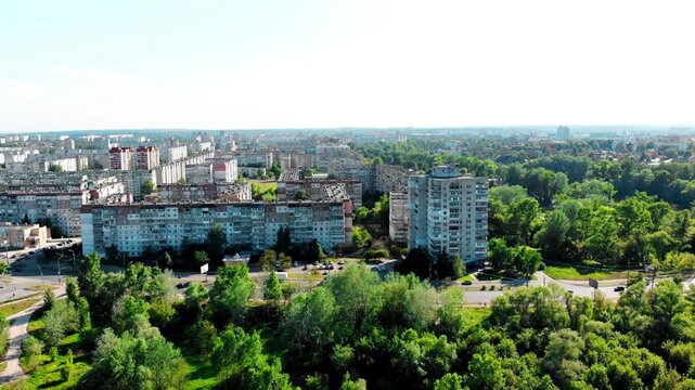 Drone shot of the 10th microdistrict in Sumy, Ukraine, with densely built-up residential buildings in a typical residential area. Busy road with moving traffic, green urban areas. 