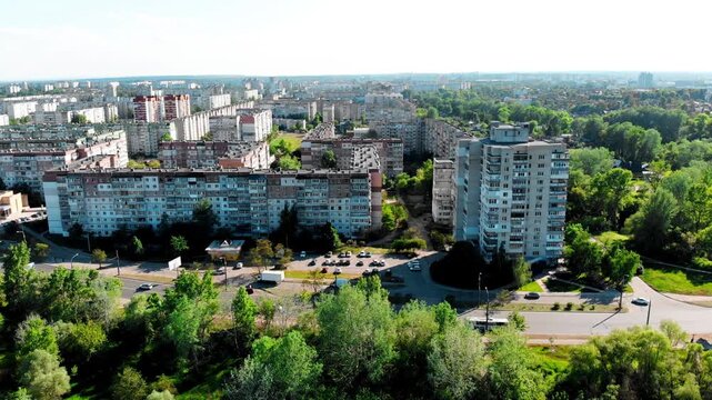 Drone shot of the 10th microdistrict in Sumy, Ukraine, with densely built-up residential buildings in a typical residential area. Busy road with moving traffic, green urban areas. 
