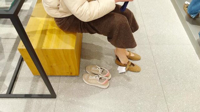 Shopper Trying On Flat Shoes In Store. Choosing Product In Apparel Shop