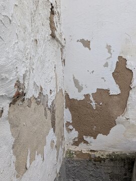 Decayed Wall Backdrop. Old Plaster Surface Exposing Raw Material With Flaking Paint And Damp Stains