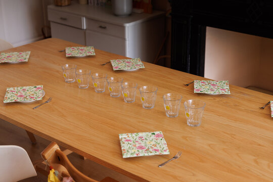 Glasses on a wooden table ready for a kids party. All the glasses have stickers with the kids' name on them.