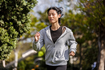 Fototapeta premium Young woman exercises in a park in Spain, jogging outdoors in the daytime