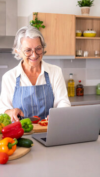 Seniorin in der K&uuml;che sucht online nach Rezepten am Laptop