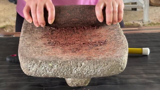 Closeup of Grinding Roasted and Dried Cacao Beans With a Stone to Make Chocolate