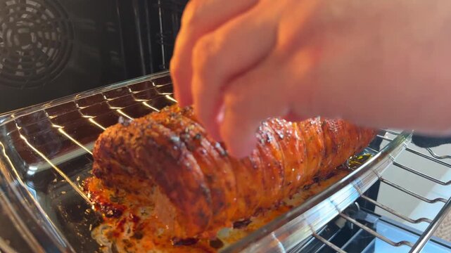 Roasted pork roll in oven with thermometer. Hand removes probe and juices flow from meat, showing tenderness, doneness, and precise home cooking process with crispy crust.