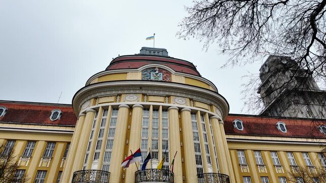 Historic city hall with clock tower and surrounding architecture in Senta Serbia under cloudy sky, highlighting urban heritage, administration and European cityscape