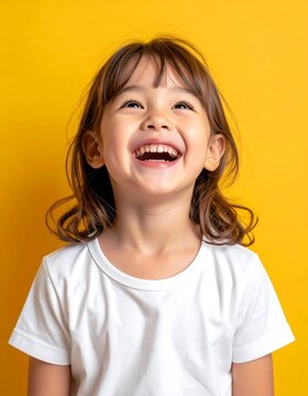 Portrait of a young child with long brown hair wearing a white shirt and smiling widely, gazing upwards. Yellow background