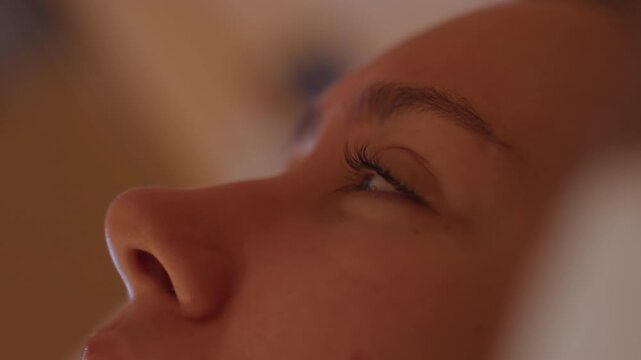 Intimate breathing exercise. Closeup of face engaging in calm breathing under gentle illumination. Intimate facial focus showing mindful breathing practice within warmly lit hotel environment