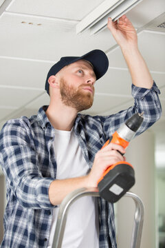 male worker using cordless tool to install new light