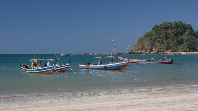 Fishing boats anchored near sandy beach in Ngapali Myanmar, tropical coastline in Southeast Asia.