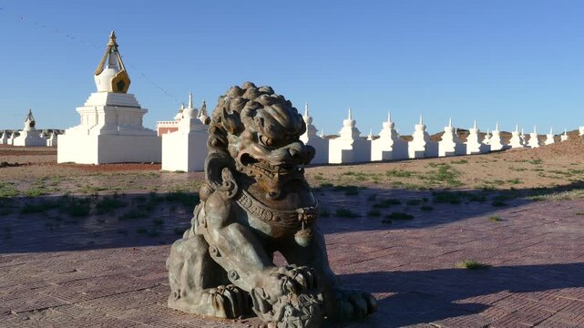  Buddhist architectural complex Shambala in the Gobi desert, Mongolia. Bronze sculpture of the guardian lion in the foreground. Stupas - ritual Buddhist buildings.
Hot summer Sunny day.