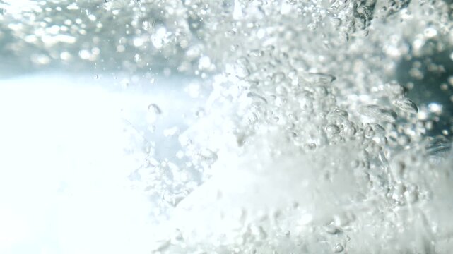 Ice cubes falling into water with oxygen bubbles, frost patterns, and soft light reflections. Concepts for beauty advertising, menu designs for bars and restaurants, cryotherapy.