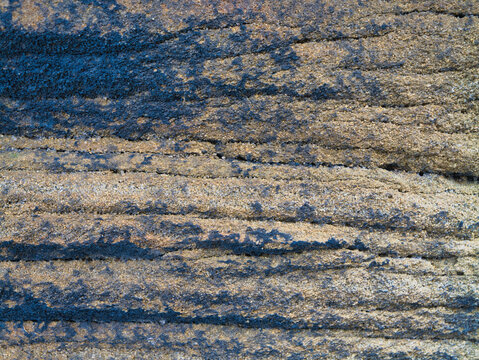 Close up of millstone grit with layered rough texture and cool blue shadows in Yorkshire UK, ideal as a natural stone background.