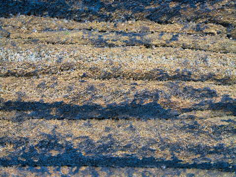 Close up of layered millstone grit in Yorkshire UK with coarse grain and earthy tones creating a rugged natural texture background