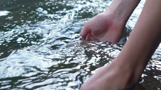 Young woman drinking fresh water from a clean forest stream in summer. Pure nature, peace, and refreshment. A quiet moment in the wilderness, symbol of connection with nature and natural living.