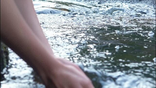 Young woman drinking fresh water from a clean forest stream in summer. Pure nature, peace, and refreshment. A quiet moment in the wilderness, symbol of connection with nature and natural living.